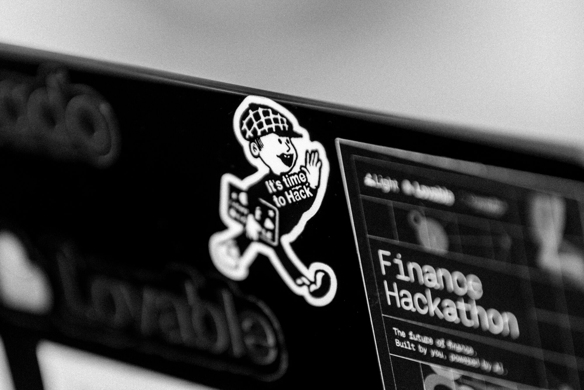 It's time to Hack, the sticker on a builder's laptop beside the Finance Hackathon brief